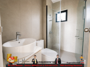 Modern beige-tiled bathroom with a white oval sink, chrome faucet, toilet, and a glass-enclosed shower with a rainfall head and handheld shower.