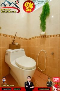 Modern white toilet in peach-tiled bathroom with a hanging green plant and property advertising banners above.