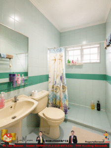 Mint-green tile bathroom with a sea-themed shower curtain, cream sink and toilet, window with bars, and toiletries on a shelf and ledge near the mirror