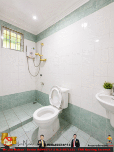 Bathroom with white tiled walls and teal floor/trim, toilet with open lid, and wall-mounted electric shower unit nearby; sink with small plant on it and a barred window above.