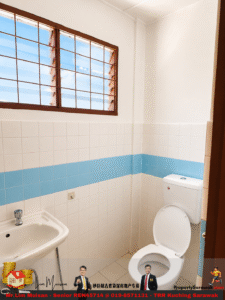 Small bathroom with a white toilet and sink, white tiles with a blue horizontal stripe, and a large barred window.