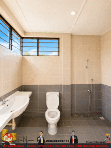 Public bathroom with beige and gray tiled walls, a white toilet center, a sink on the left, and a handheld shower on the right under a high window bringing in blue sky.