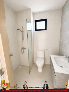 Small modern bathroom with a glass shower partition, wall-mounted shower, toilet, and a marble-slab sink along a gray tiled wall; a high rectangular window lets in natural light.