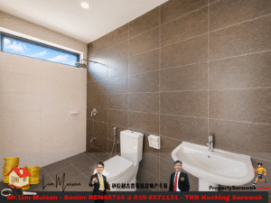 Modern bathroom with brown tiled wall, white toilet and pedestal sink, and a showerhead on the left under a high horizontal window.