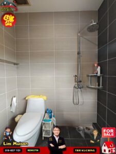 Modern bathroom with gray tiled walls, a rainfall shower head, glass panel, and toilet with a yellow towel on top. A small rack holds toiletries by the shower amid promotional overlays in the corners.