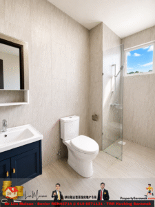 Modern bathroom with beige tiled walls, a white toilet, navy vanity, and a glass-enclosed shower under a window showing a blue sky.