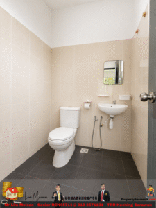 Small beige-tiled bathroom with a white toilet and wall-mounted sink, a rectangular mirror above, and a handheld bidet hose near the sink.