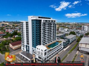 Aerial view of a modern white and teal high-rise building with a rooftop pool, set in a dense cityscape under a blue sky, used as a real estate promotional image.