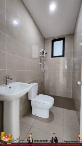 Compact beige-tiled bathroom with pedestal sink, toilet, and a handheld shower; frosted window high on the wall.